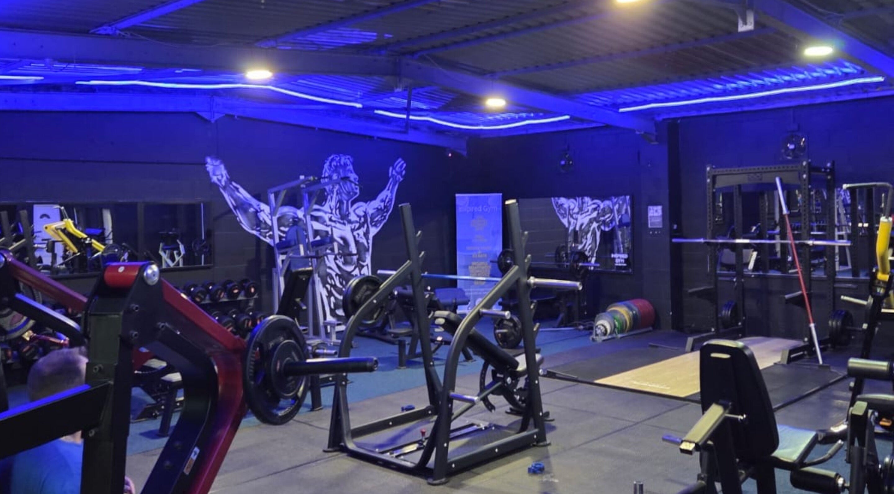 Modern gym interior at 360 Healthcare Hub, Wigan, England, GB with weightlifting equipment and bold wall art.