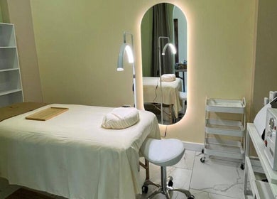 Sala de tratamiento en ZACI SPA, Tijuana, Baja California, MX, con mesa de masaje blanca y espejo iluminado.