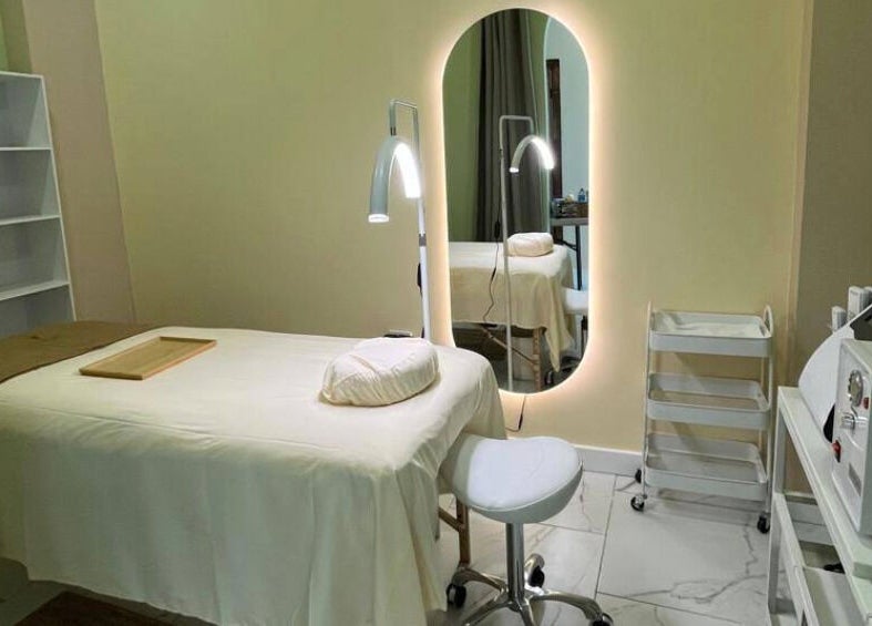 Sala de tratamiento en ZACI SPA, Tijuana, Baja California, MX, con mesa de masaje blanca y espejo iluminado.