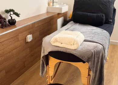 Cozy massage room at Aurora Holistics by Tracy, Midsomer Norton, England, GB with wooden decor and plush towels.