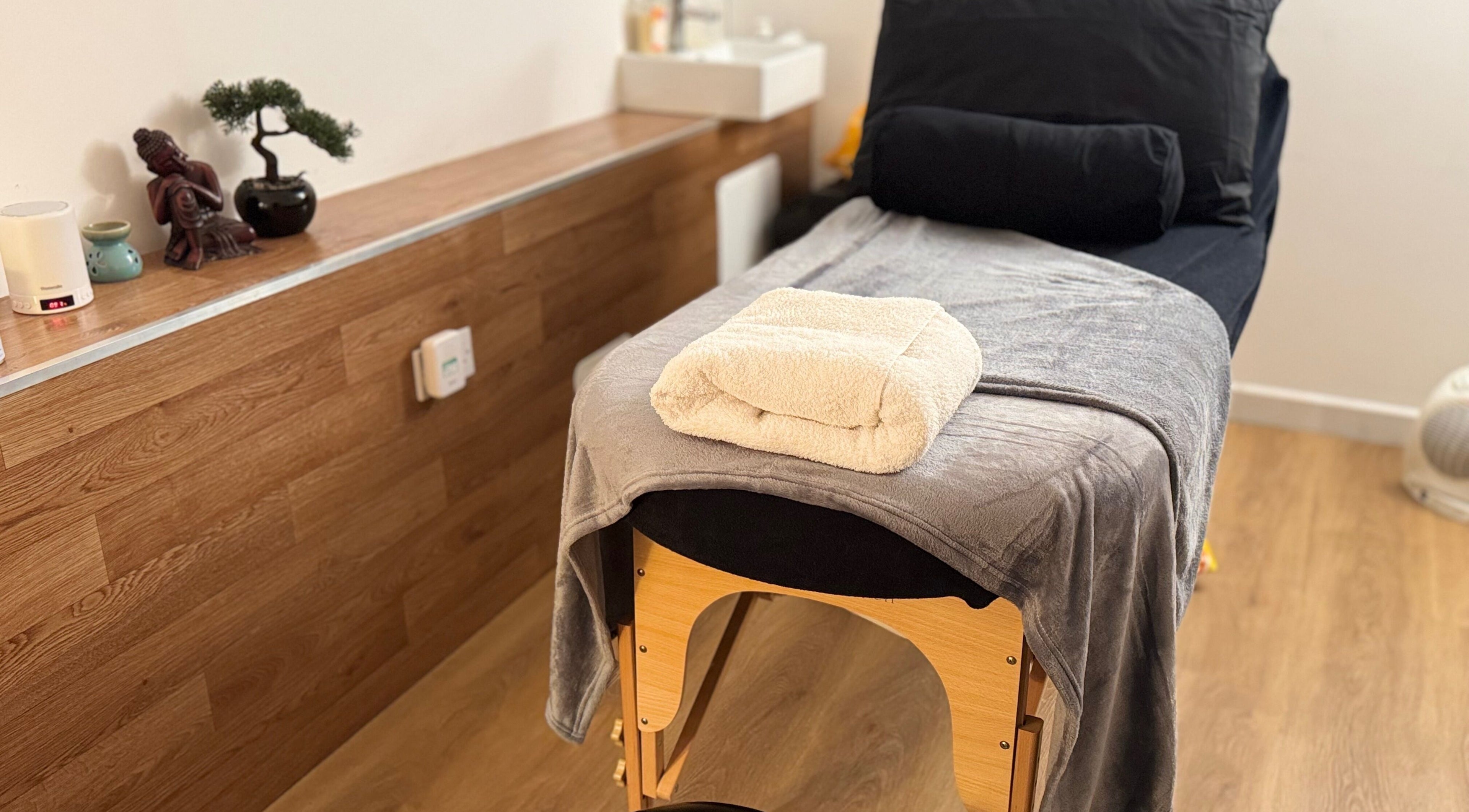 Cozy massage room at Aurora Holistics by Tracy, Midsomer Norton, England, GB with wooden decor and plush towels.