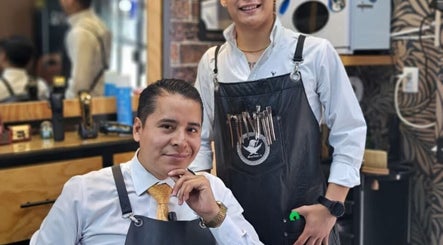 Dos barberos en Lord Of Lords Barber, Ciudad De México, MX, sonríen junto a herramientas profesionales.