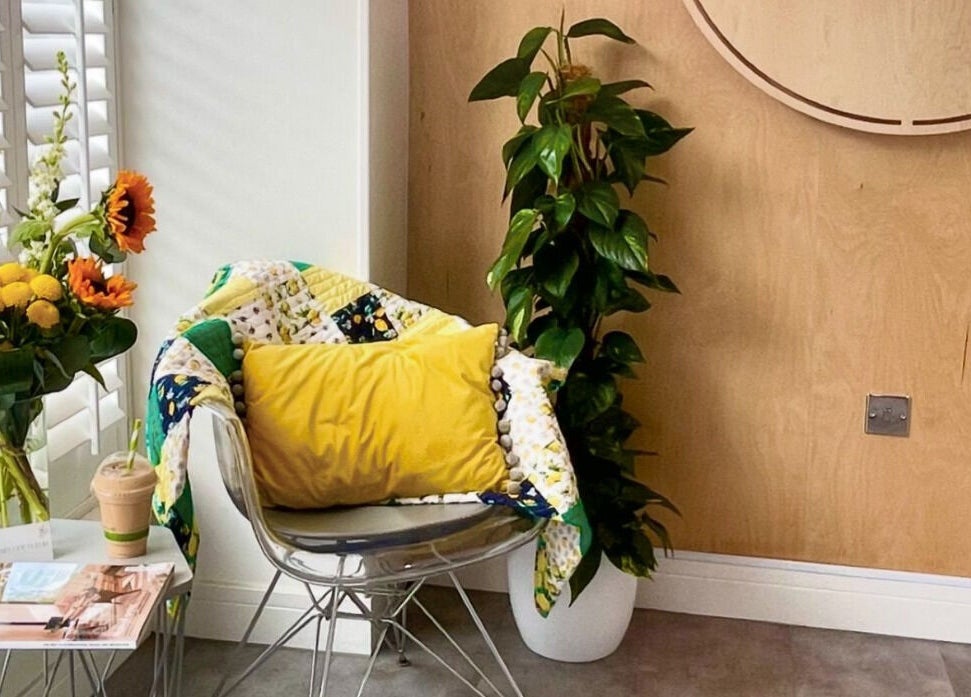 Cozy chair with yellow cushion and flowers at Citrus Hair Bar, Edinburgh, Scotland, GB.