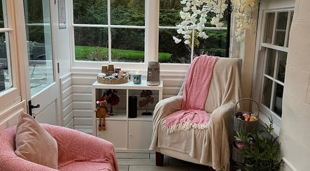 Inviting seating area at Kris's Nails, Washaway, England, GB, with plush pink chairs and elegant decor.