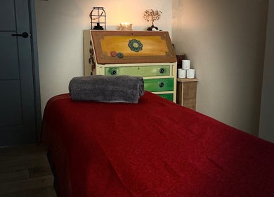 Cozy massage table at Moon 8 Holistics, Wickham, England, GB, with candles and a towel for relaxation.