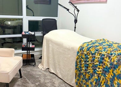Cozy treatment room at Winked Studio, Toronto, Ontario, CA with plush chair and colorful blanket.