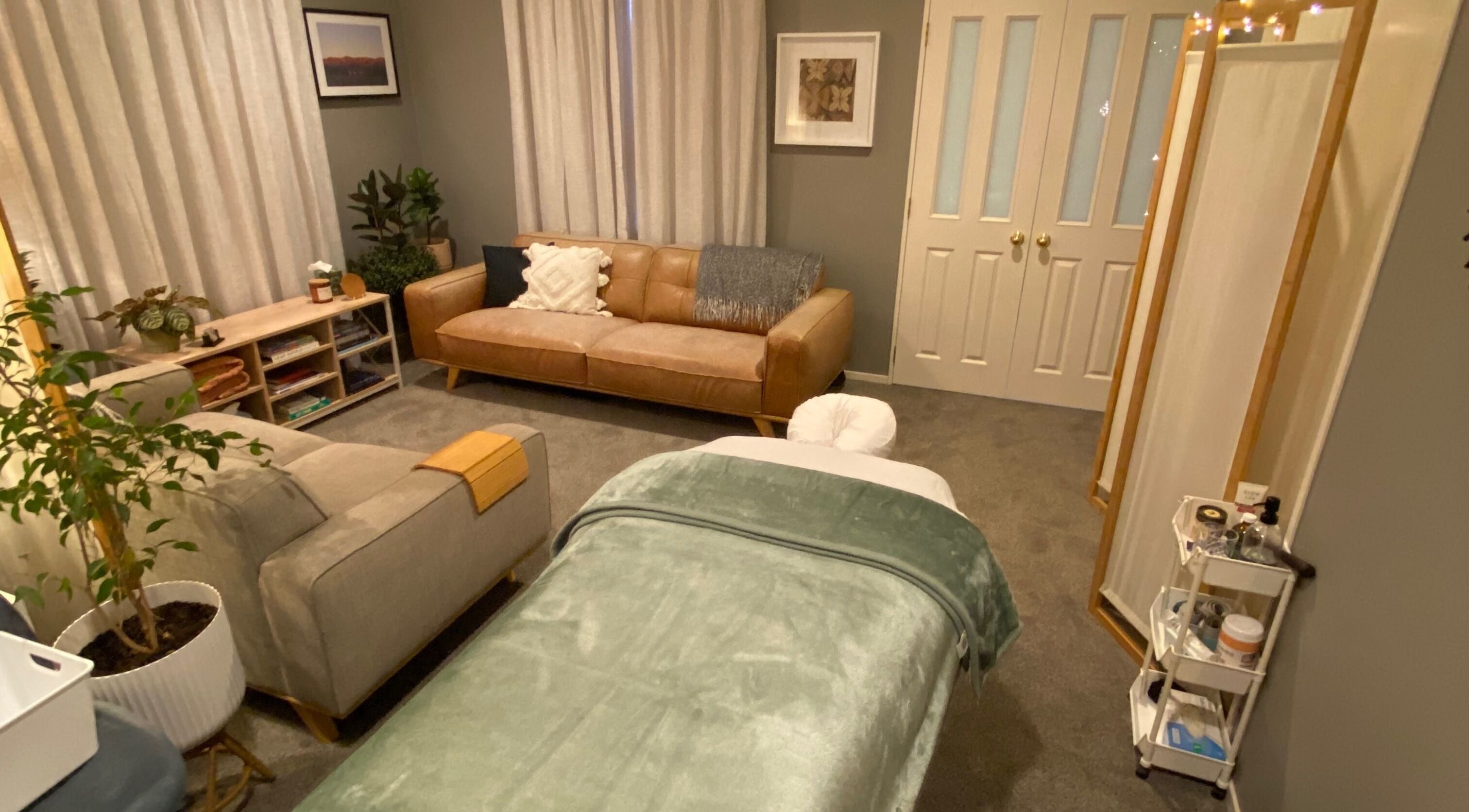 Cozy massage room at Muscles & Mind, Hamilton, Waikato Region, NZ with a plush sofa and colorful decor.