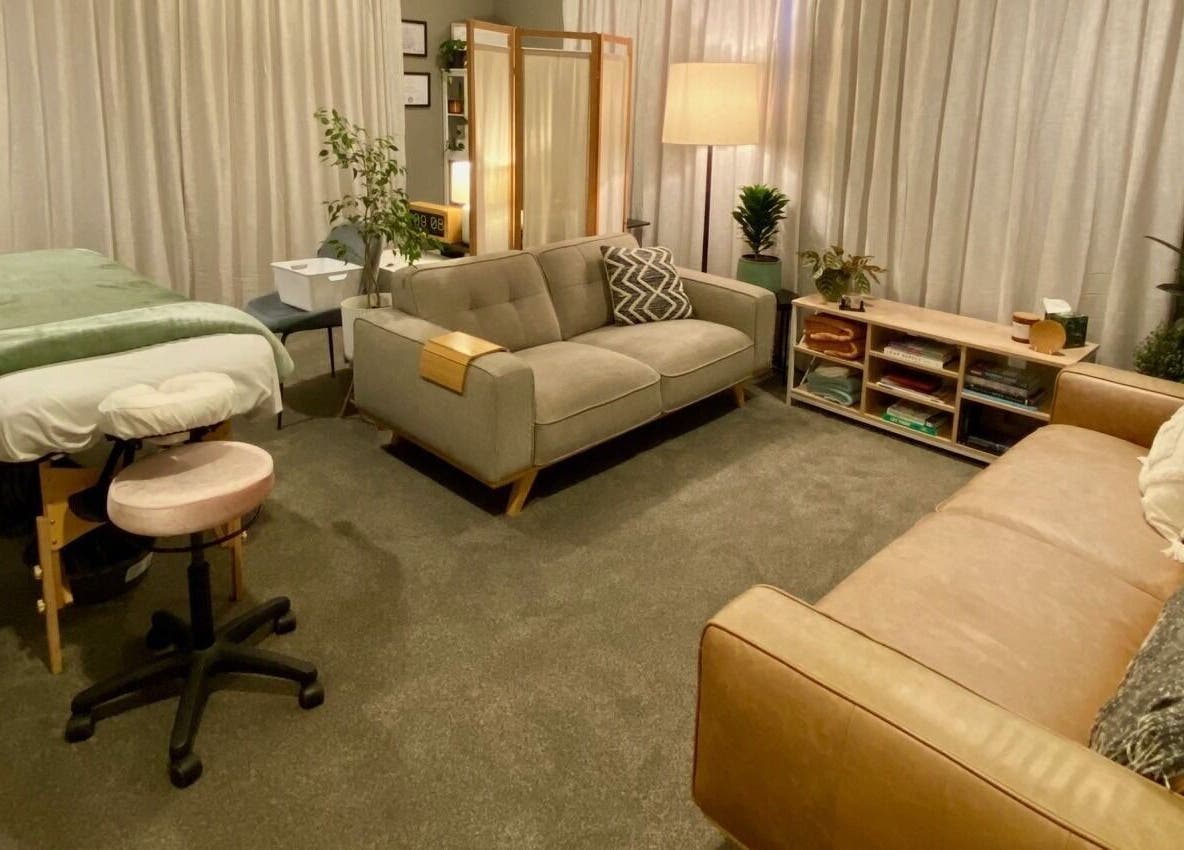 Tranquil therapy room at Muscles & Mind, Hamilton, Waikato Region, NZ, featuring massage table and cozy seating.