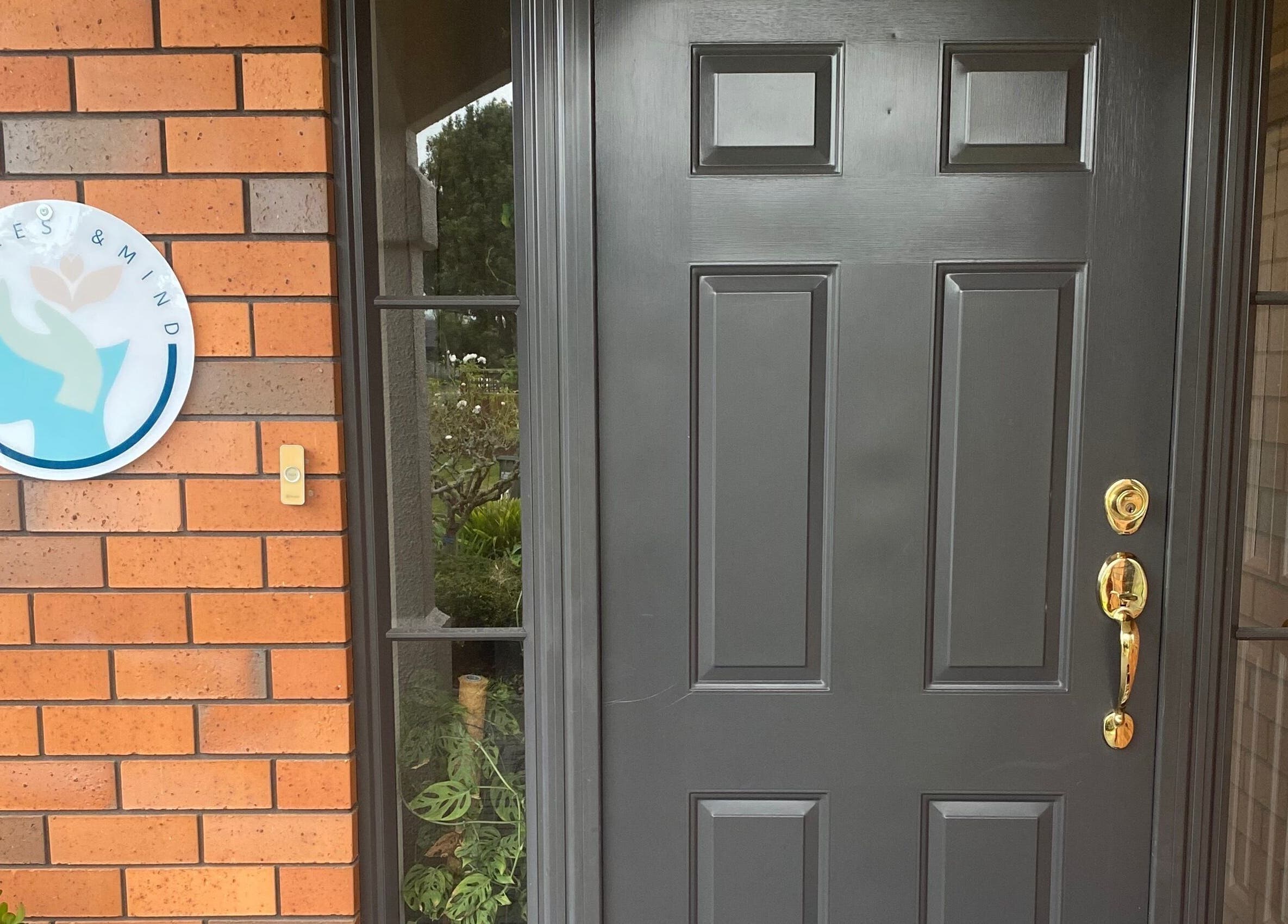 Entrance of Muscles & Mind in Hamilton, Waikato Region, NZ with logo and dark door.