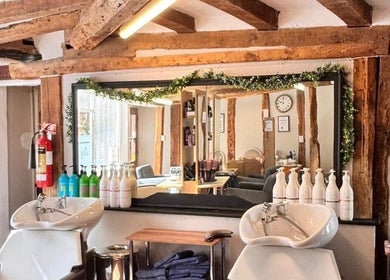Rustic salon interior at The Cutting Co., Woodbridge, England, GB with wooden beams and modern wash stations.