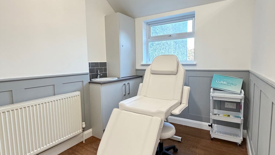 Bright, modern treatment room at Kira Aesthetics, Coalville, England, GB featuring a white chair and workspace.
