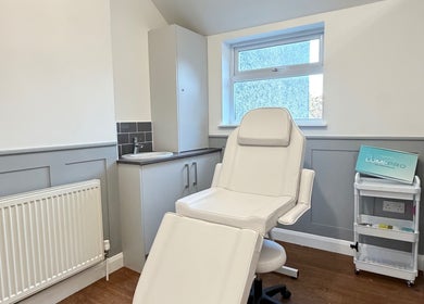 Bright, modern treatment room at Kira Aesthetics, Coalville, England, GB featuring a white chair and workspace.