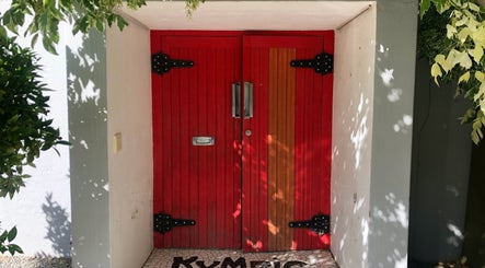 Red wooden door at Kymric Hall, Franschhoek, Western Cape, ZA, framed by green foliage.
