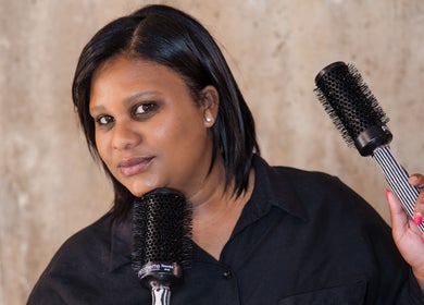 Professional hairstylist at Kymric Hall, Franschhoek, Western Cape, ZA, holding round brushes for hair styling.