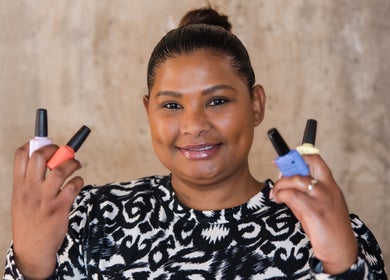 Smiling person holding colorful nail polishes at Kymric Hall, Franschhoek, Western Cape, ZA.