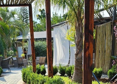 Lush garden view at Konanani Massage & Spa in Polokwane, Limpopo, ZA under a shaded patio.