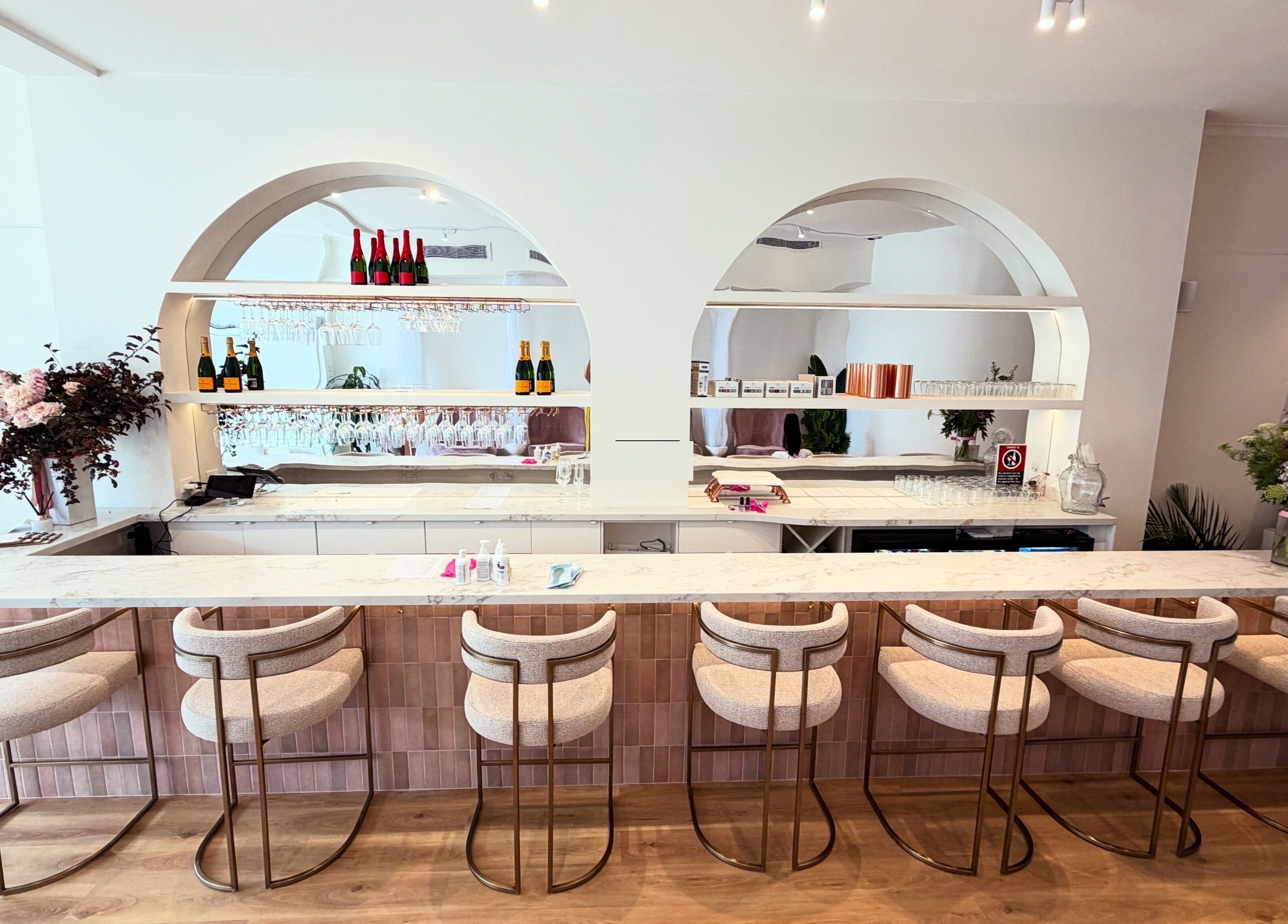 Chic bar area at Melt Nail Bar in Bronte, New South Wales, AU featuring stylish stools and floral arrangements.