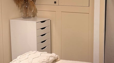 Serene massage room at All About Beauty, Ripley, England, GB with elegant decor and storage.