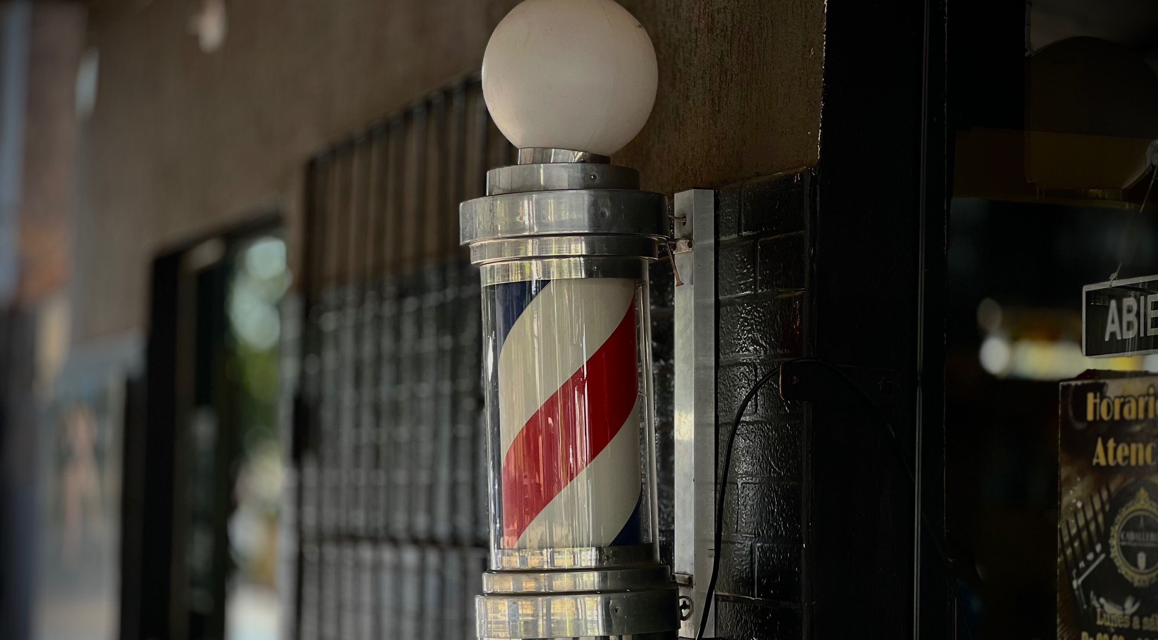 Faro clásico de barbero frente a Caballeros Barbería Casa Central en Luque, Central, PY.