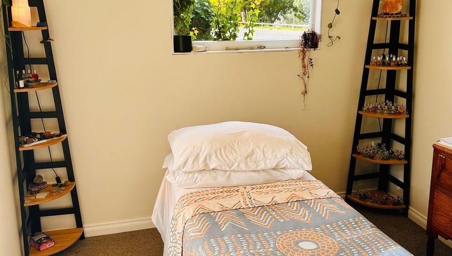 Relax in Threefold Wellness massage room, Waitara, Taranaki Region, NZ featuring a tranquil bed and essential oils.