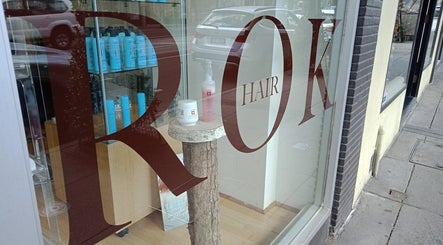 Window display at Rok Hair in Melbourne, Victoria, AU showcasing products inside a modern salon.