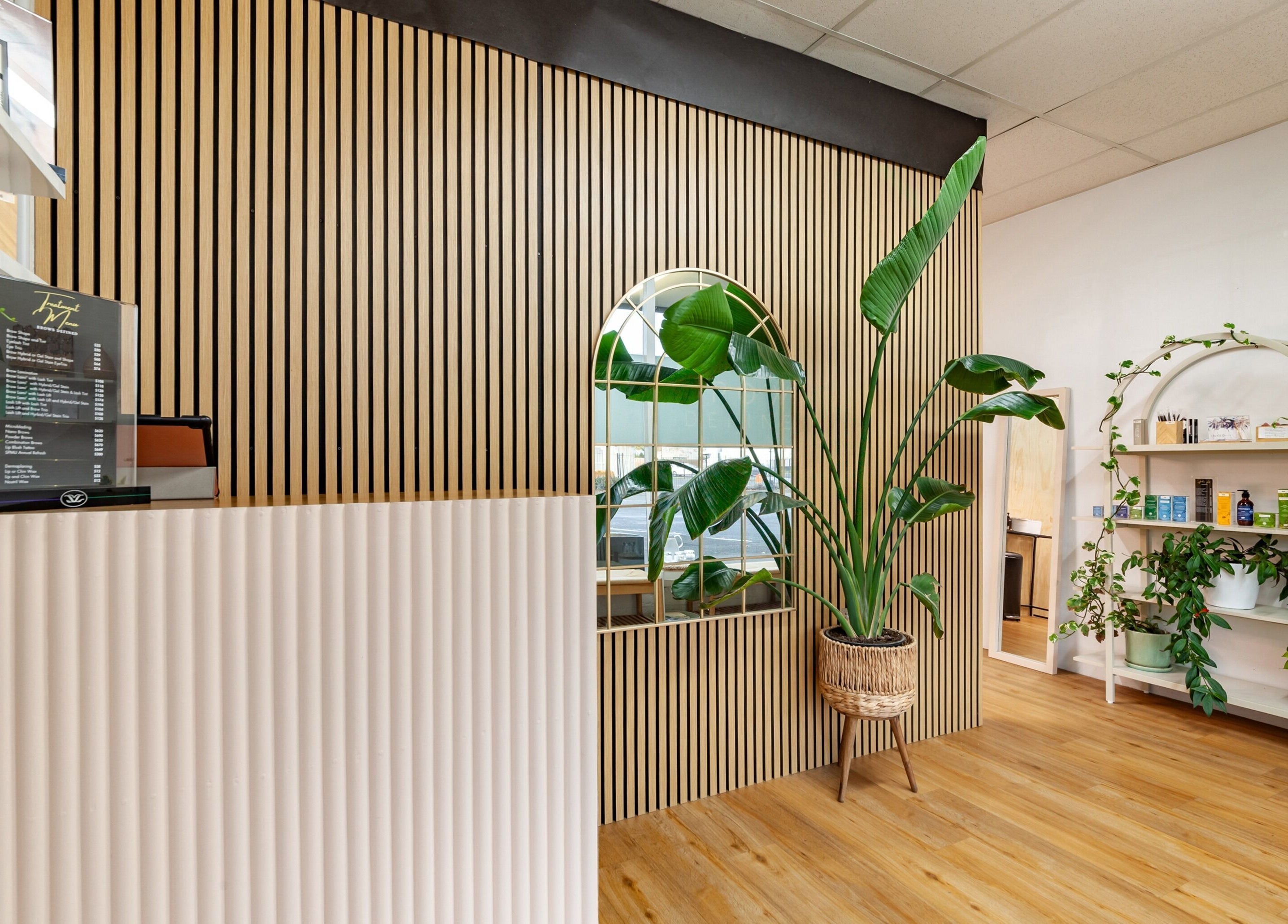 Modern interior of Brows Defined, Christchurch, Waitaha, NZ, featuring natural wood decor and lush green plants.