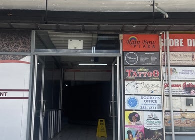 Entrance of Rainbow Plaza near Zlaynails in San-Fernando, TT showcasing store directories and signage.