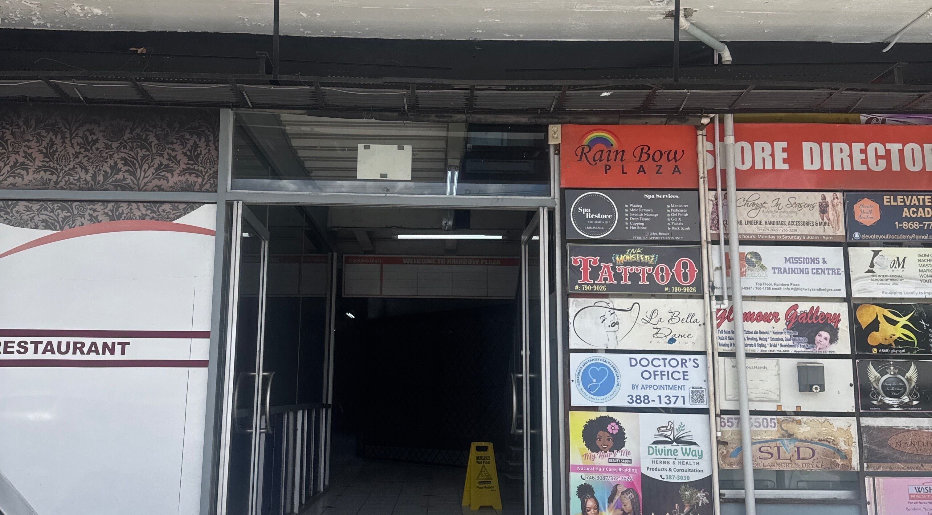 Entrance of Rainbow Plaza near Zlaynails in San-Fernando, TT showcasing store directories and signage.