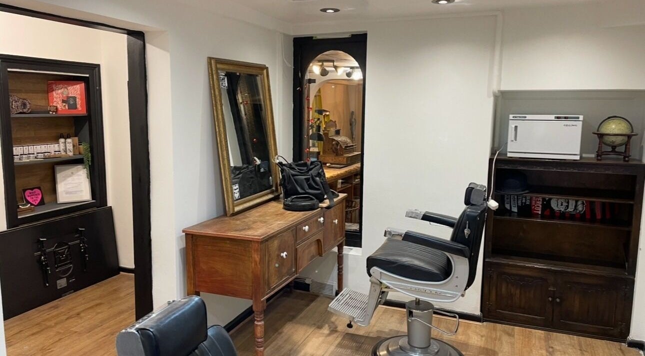 Vintage barber setup at Rudys Barbershop, St Helier, GB with chair and mirror.