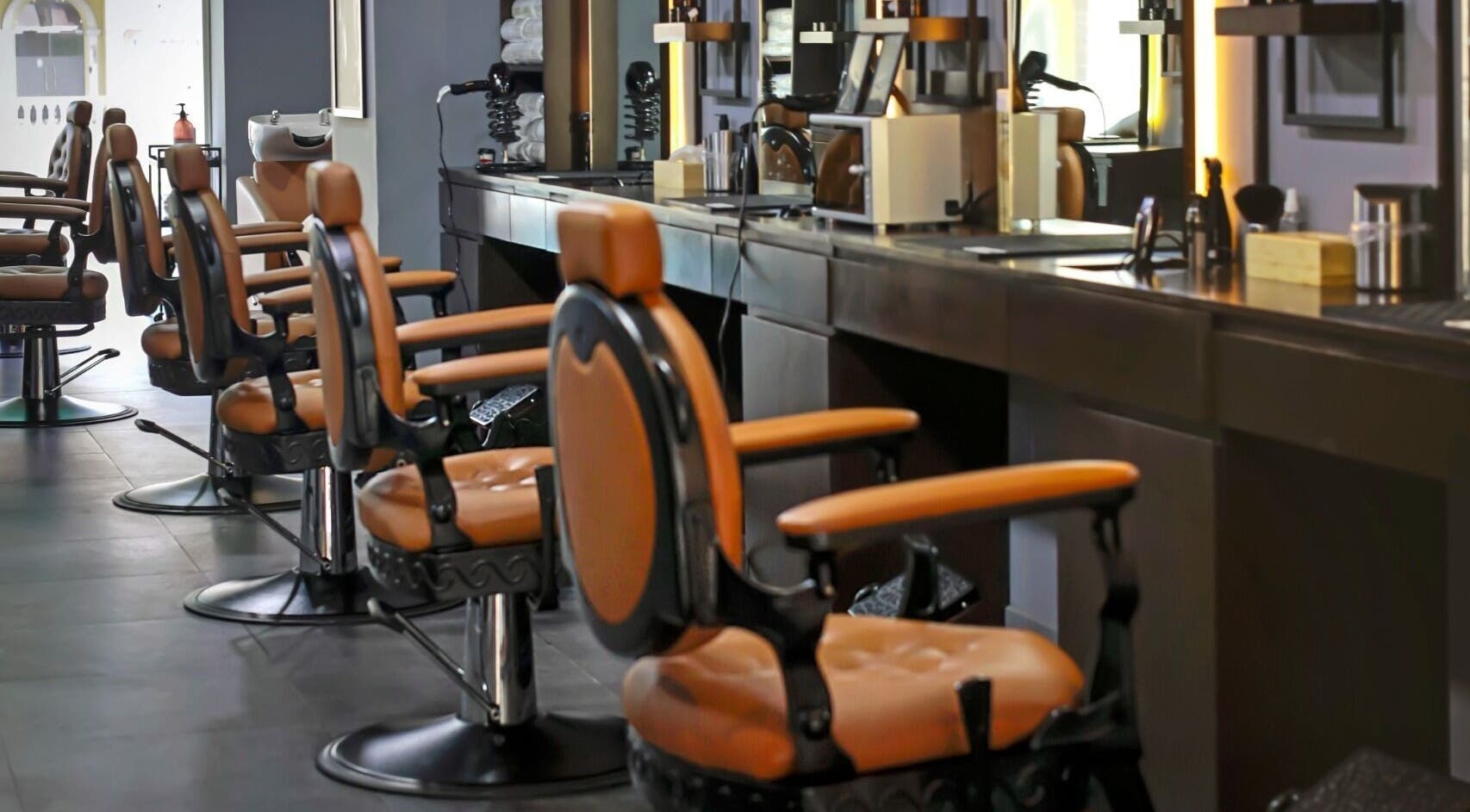 Interior of Gentlemen of London Barbershop in Doha, featuring plush leather chairs and modern styling stations.