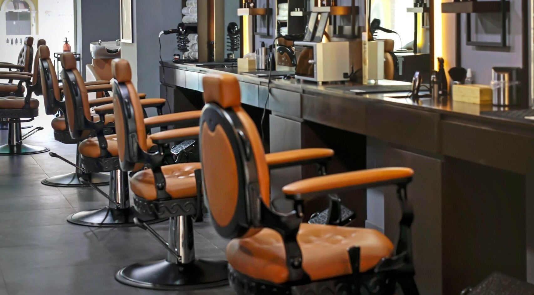 Interior of Gentlemen of London Barbershop in Doha, featuring plush leather chairs and modern styling stations.