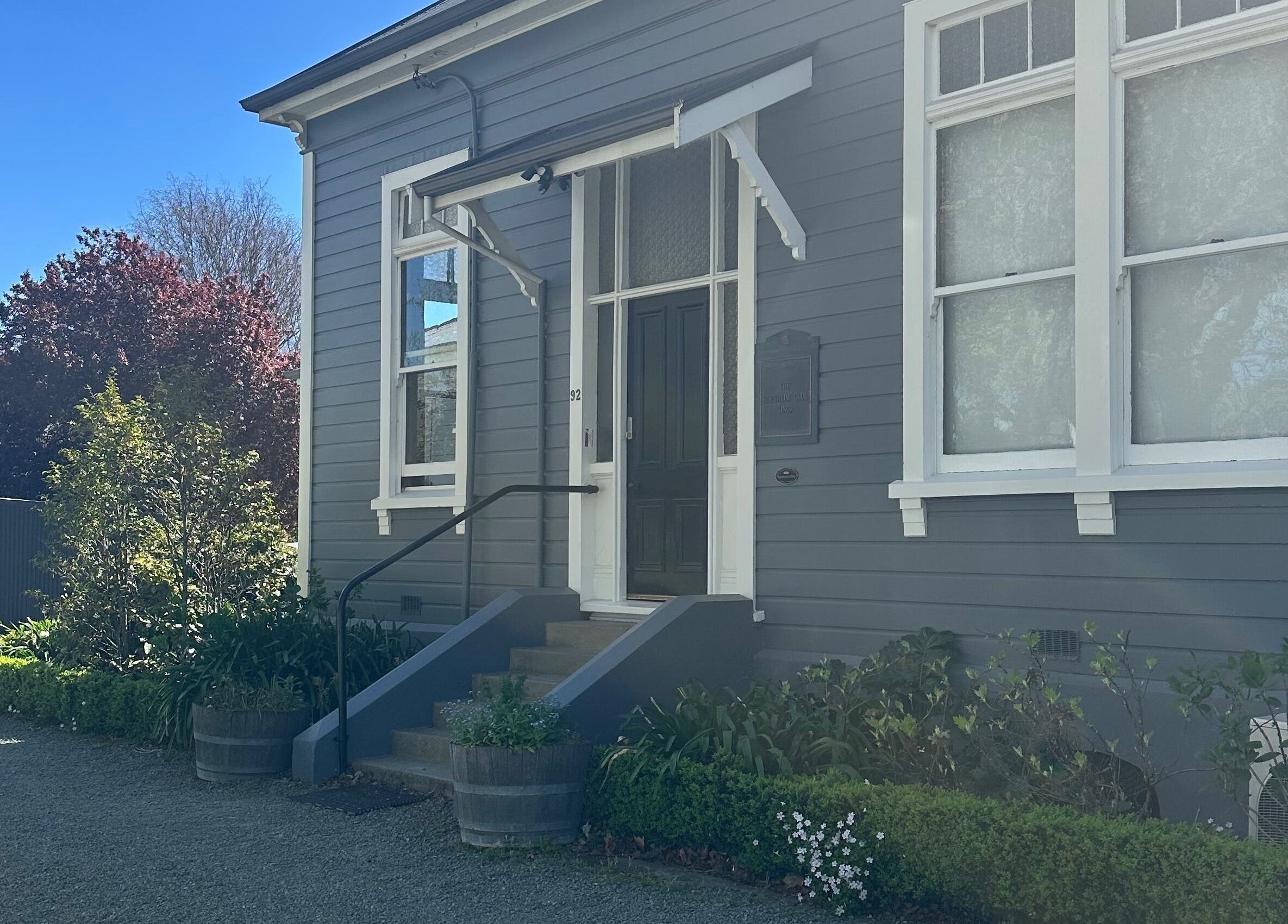 Front view of Alchemy Hair & Beauty in Blenheim, Marlborough Region, NZ with elegant entrance and lush greenery.