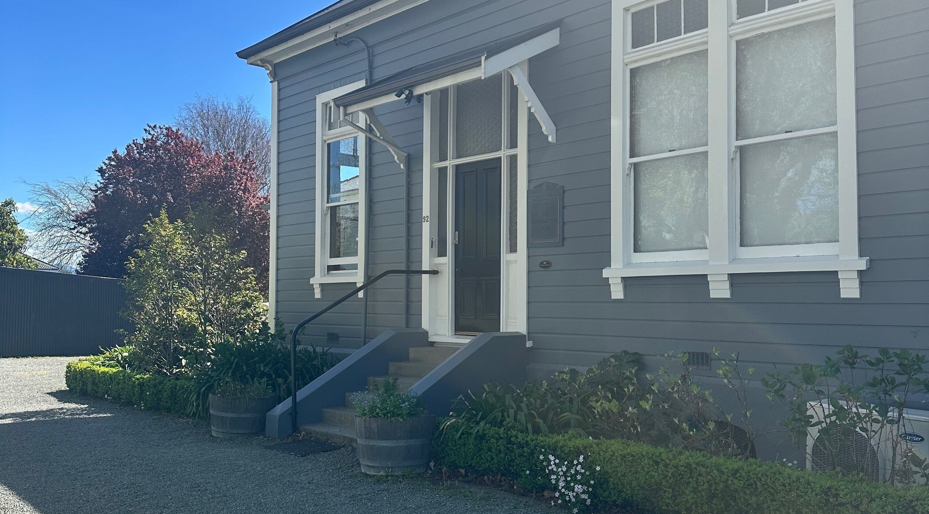 Front view of Alchemy Hair & Beauty in Blenheim, Marlborough Region, NZ with elegant entrance and lush greenery.