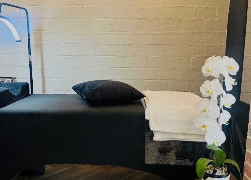 Relaxing treatment room at Lash Luxe, Cape Town, Western Cape, ZA with a sleek table and orchid decoration.