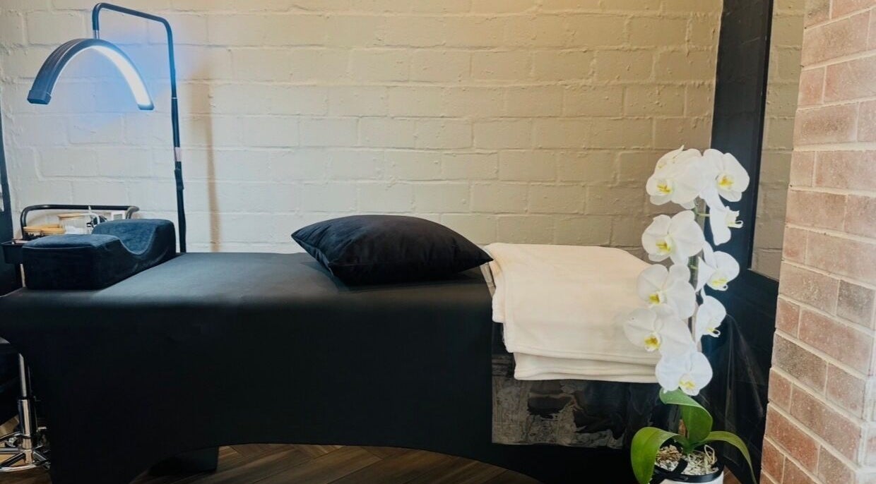 Relaxing treatment room at Lash Luxe, Cape Town, Western Cape, ZA with a sleek table and orchid decoration.