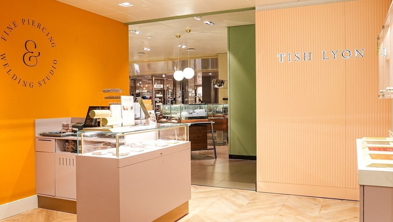 Inside Tish Lyon, London, England, GB: chic, modern piercing studio with bright orange and green accents.