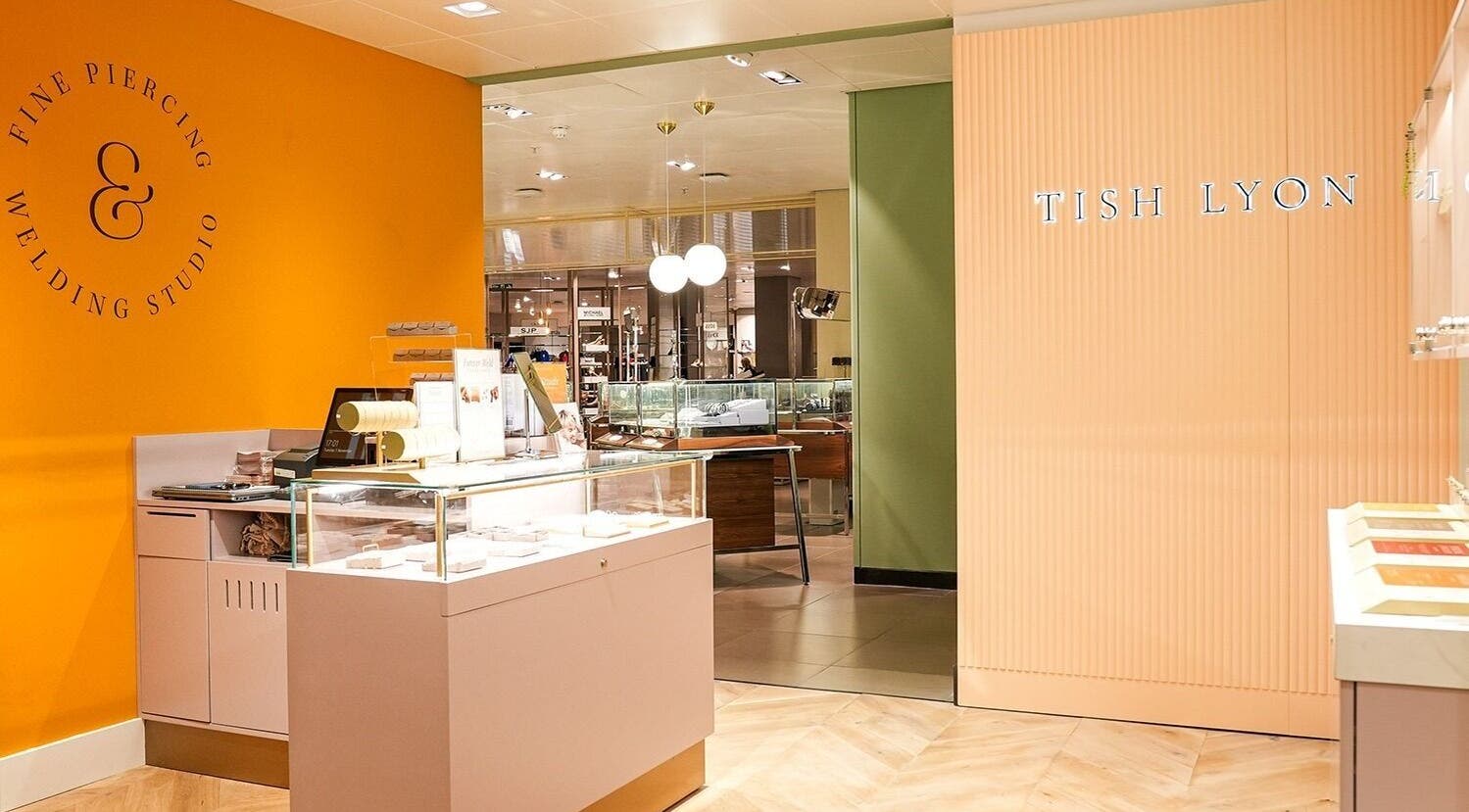 Inside Tish Lyon, London, England, GB: chic, modern piercing studio with bright orange and green accents.