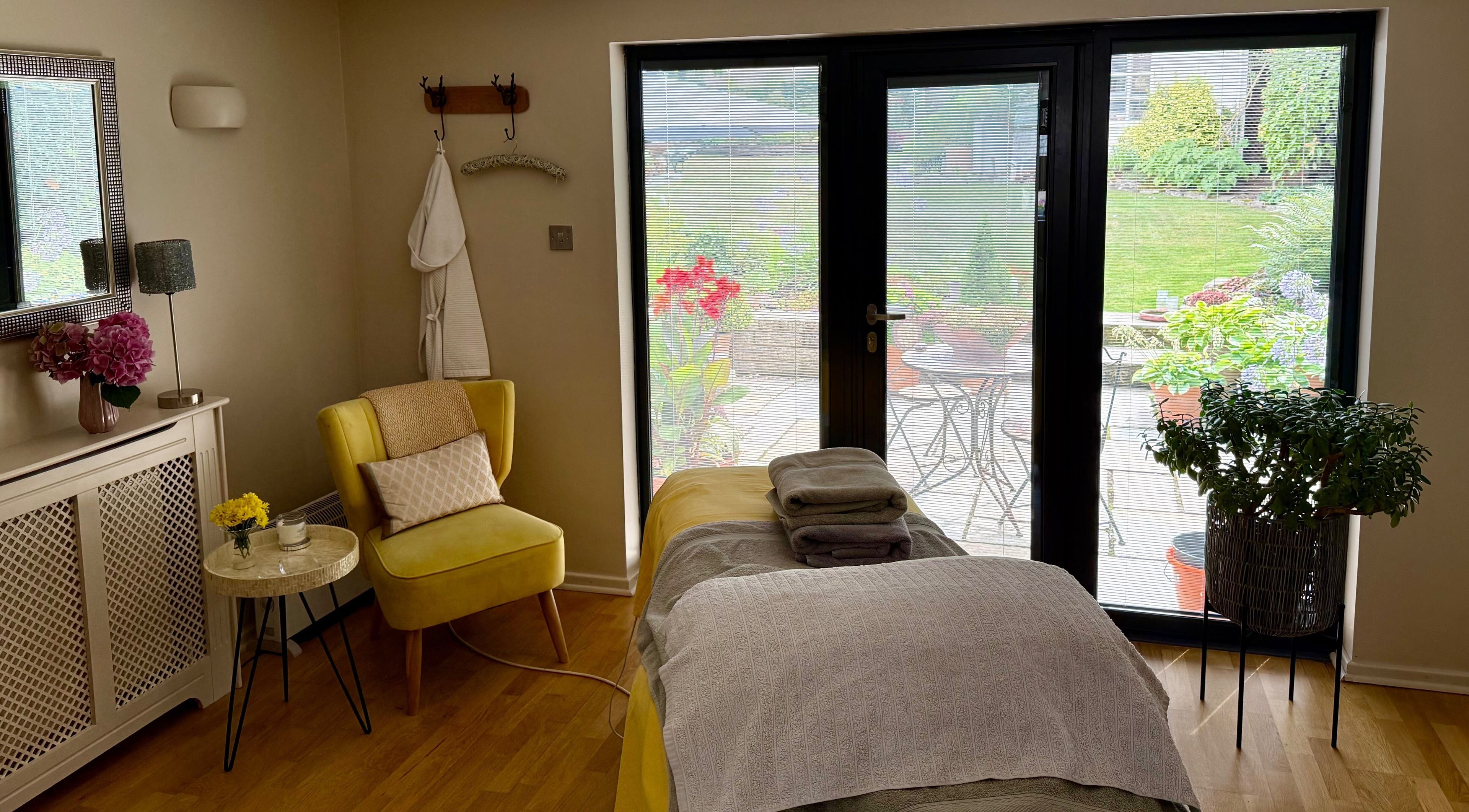 Tranquil treatment room at Katherapyuk, Crowmarsh Gifford, England, GB with a cozy chair and garden view.