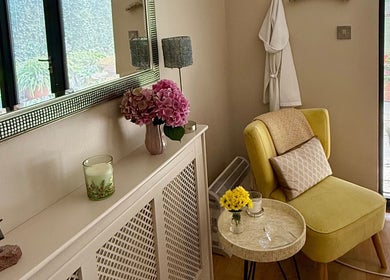 Relaxing corner at Katherapyuk, Crowmarsh Gifford, England, with a yellow chair and flowers by a sunny window.