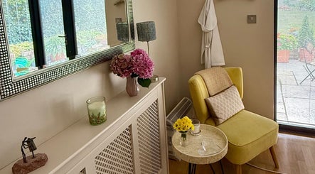 Relaxing corner at Katherapyuk, Crowmarsh Gifford, England, with a yellow chair and flowers by a sunny window.