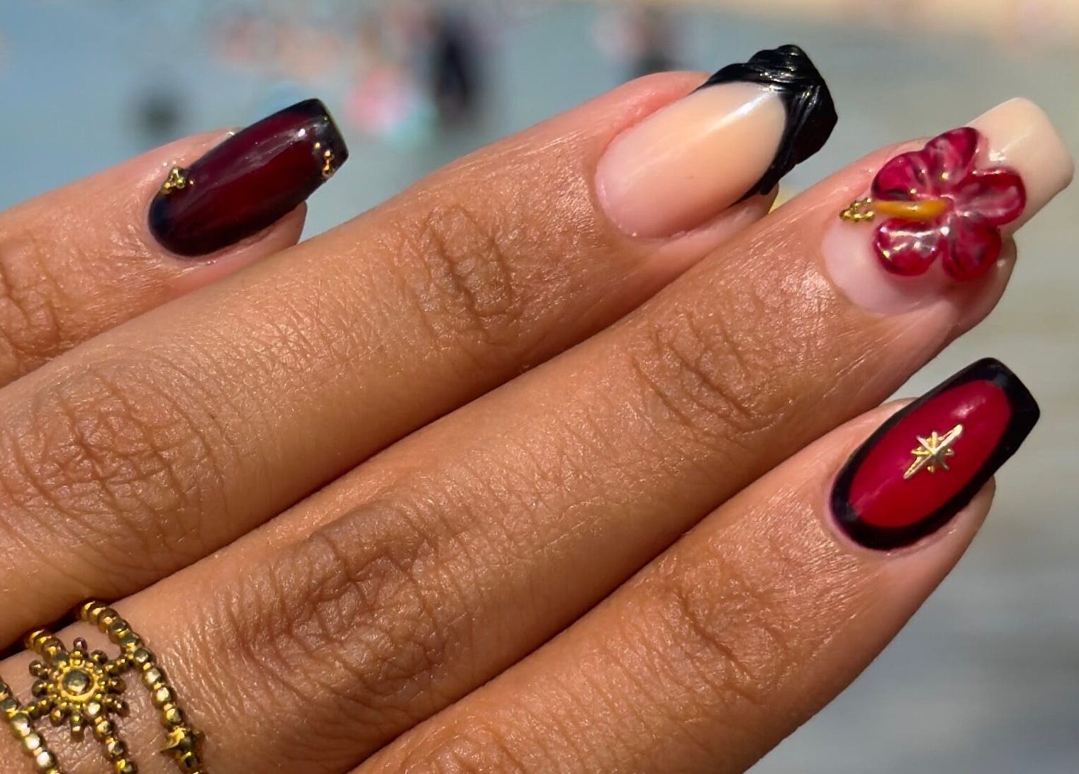 Manicura floral en FaerieClawz by Ada, Bayamón, PR. Diseño rojo y negro con detalles dorados.
