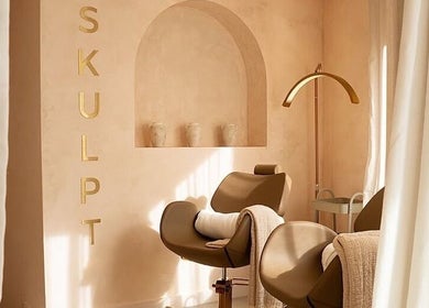 Relaxing treatment room at Mroz Beauty, Salford, England, GB, featuring stylish chairs and warm decor.