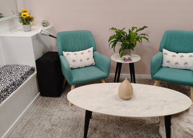 Chic relaxation area in Massage by Laura, Runaway Bay, Queensland, AU, with teal chairs and marble table.