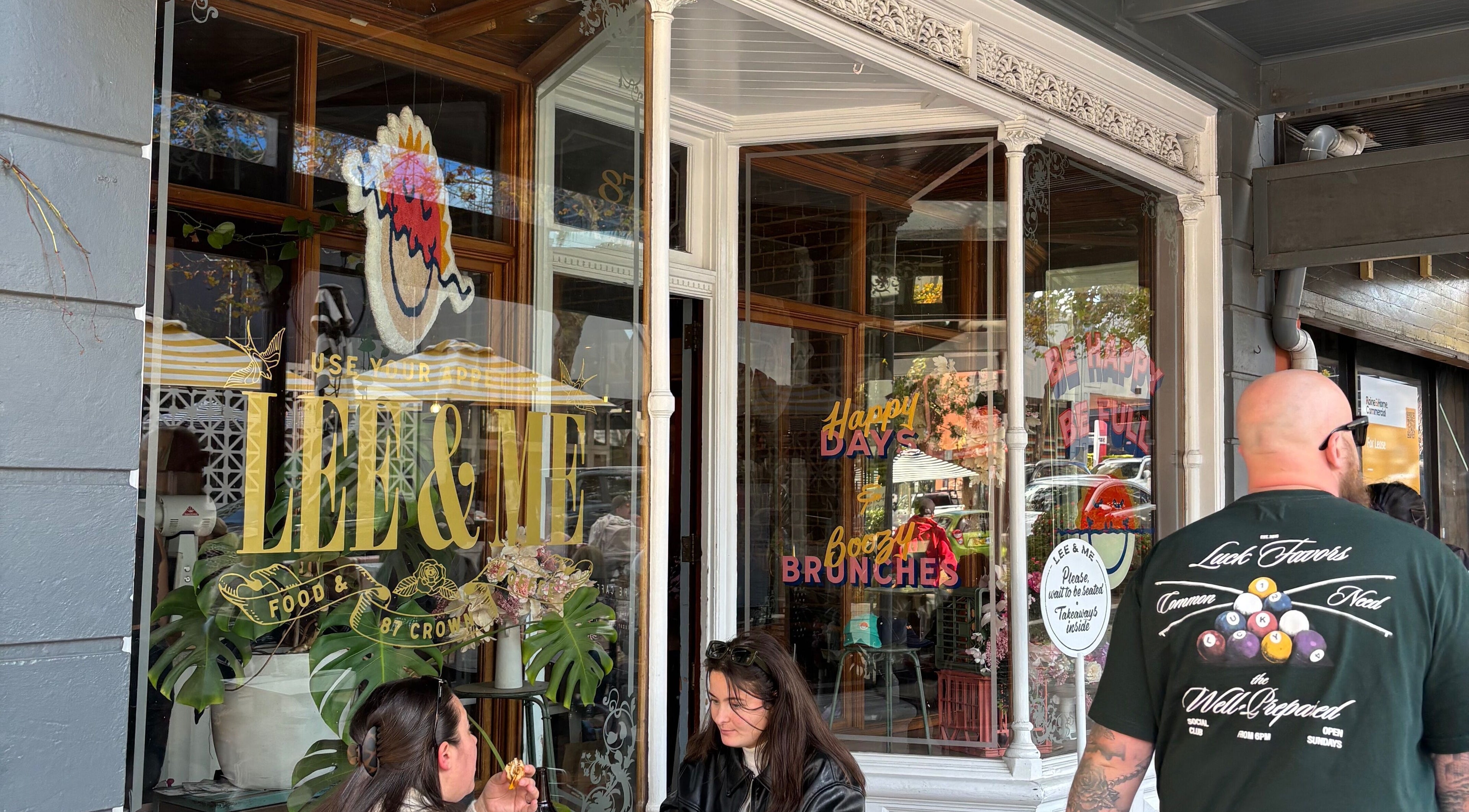 Vibrant cafe facade near Hearth Hair, Wollongong, NSW, AU showcases lively patrons and unique signage.