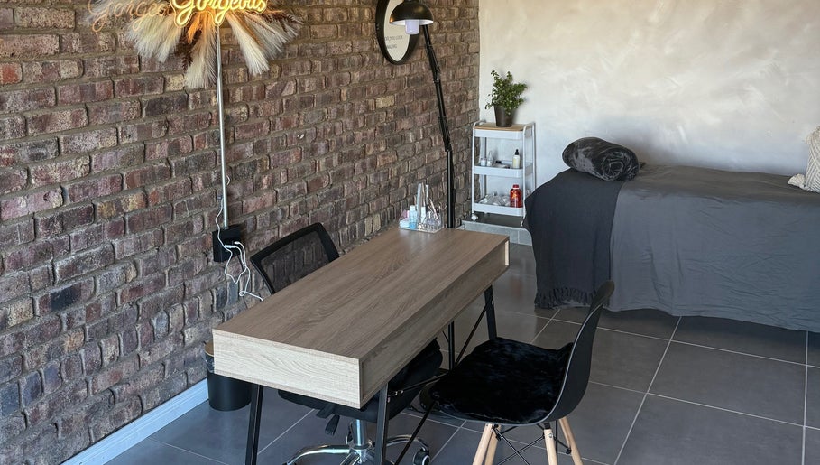 Chic treatment area at Elegant Touch Beauty, Gqeberha, Eastern Cape, ZA with brick wall and wooden table.