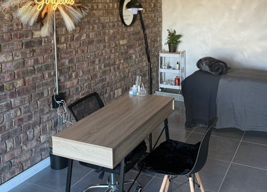 Chic treatment area at Elegant Touch Beauty, Gqeberha, Eastern Cape, ZA with brick wall and wooden table.