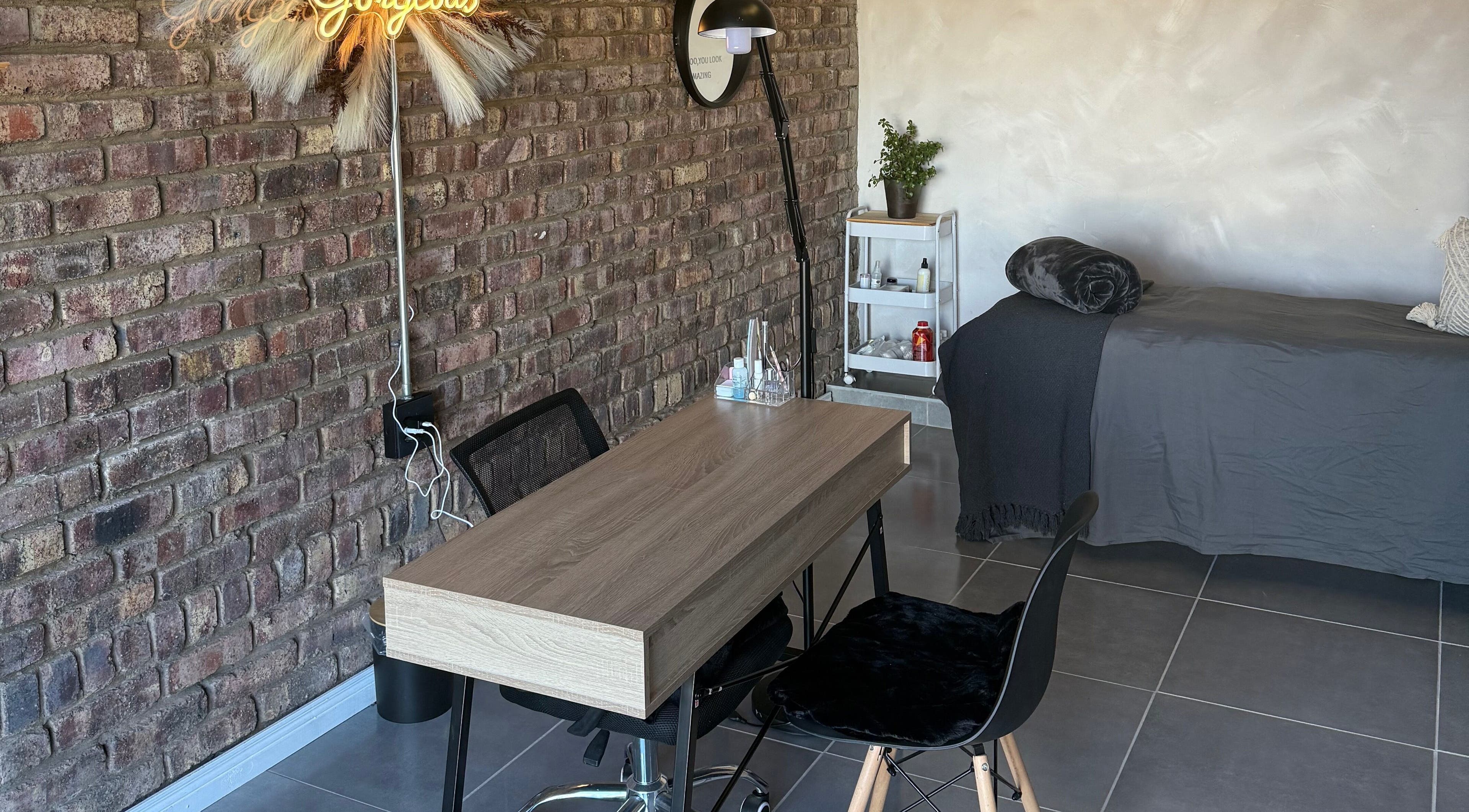 Chic treatment area at Elegant Touch Beauty, Gqeberha, Eastern Cape, ZA with brick wall and wooden table.