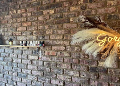 Elegant Touch Beauty, Gqeberha. Brick wall with products and glowing sign creates a cozy wellness vibe.