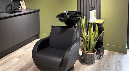Modern salon wash station at Hoipolloi Studio, Winchester, England, GB with sleek black chair and plant.
