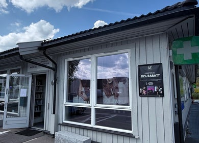 Inngang til M Beauty ved Skedsmokorset, Akershus, NO, med reklameplakater i vinduene.